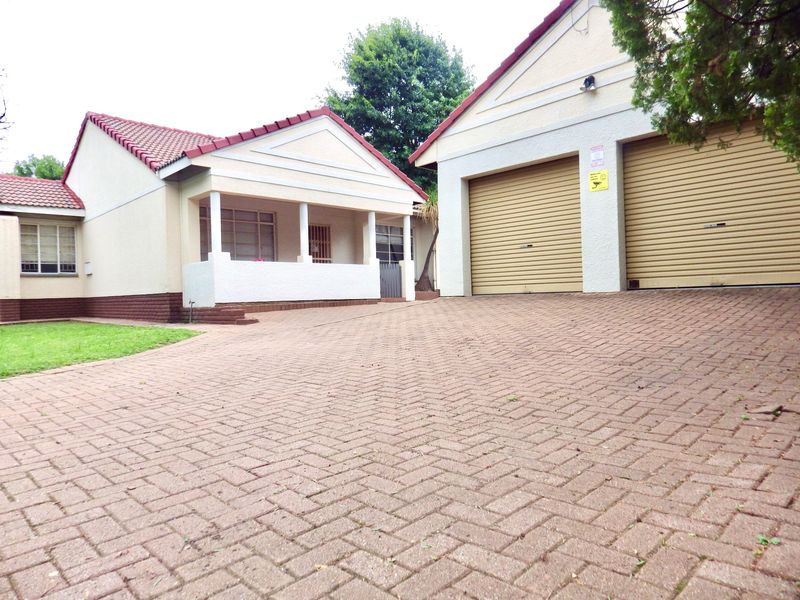 Front view of a residential property featuring a paved driveway, double garage, and a covered entrance porch with tiled roofing.