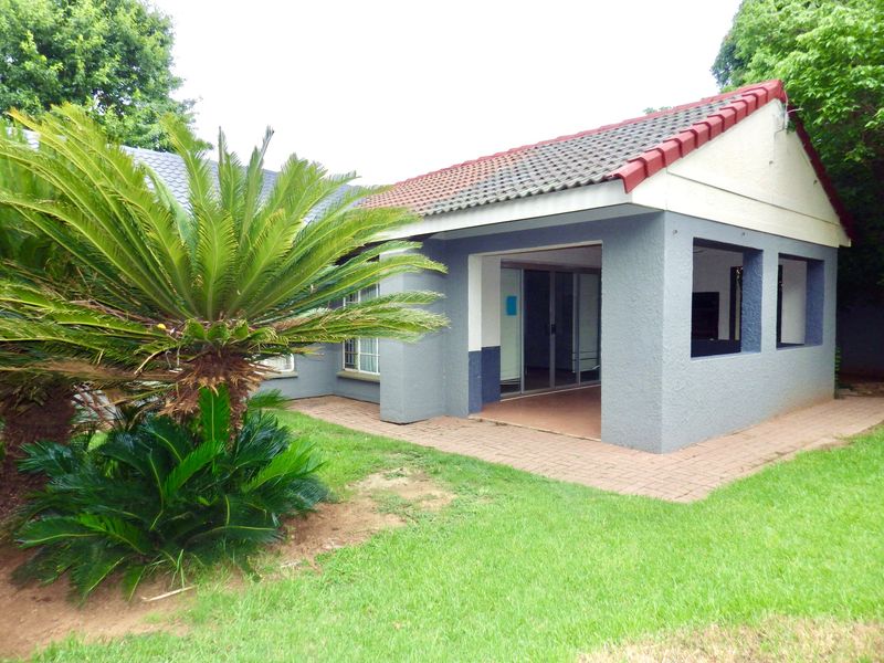Rear view of the house featuring a covered patio area with sliding glass doors, paved flooring, and a tiled roof.