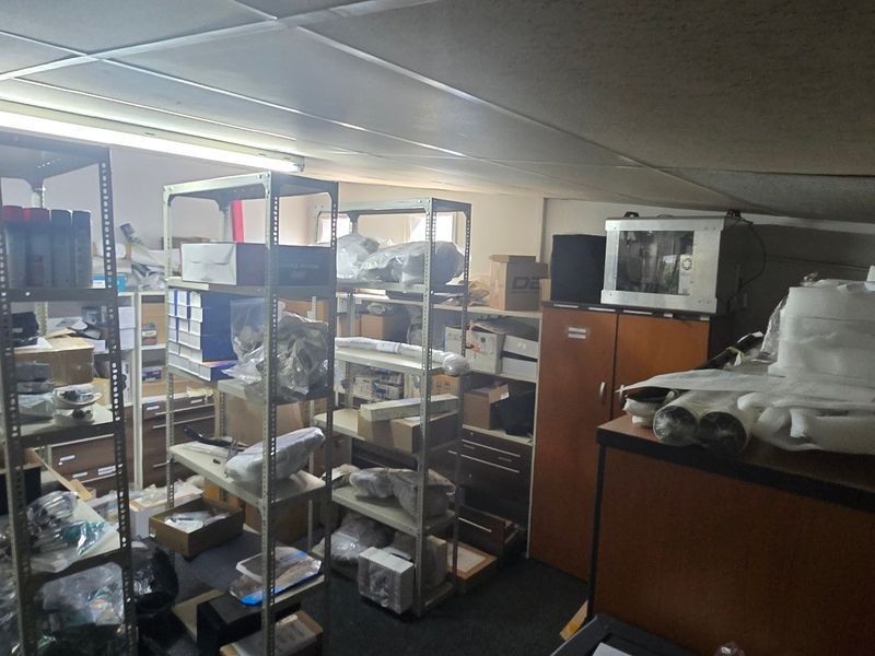 A functional utility or storage space featuring built-in cabinetry, suspended ceiling tiles, and overhead fluorescent lighting, currently utilized for industrial storage.