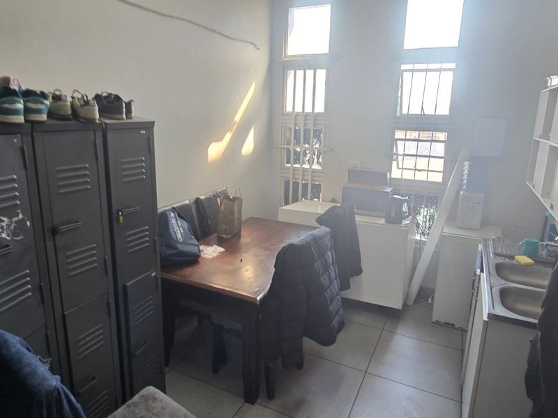 A functional industrial kitchen area featuring tiled flooring, double sink, and security-barred windows, providing a practical space for staff or utility use.