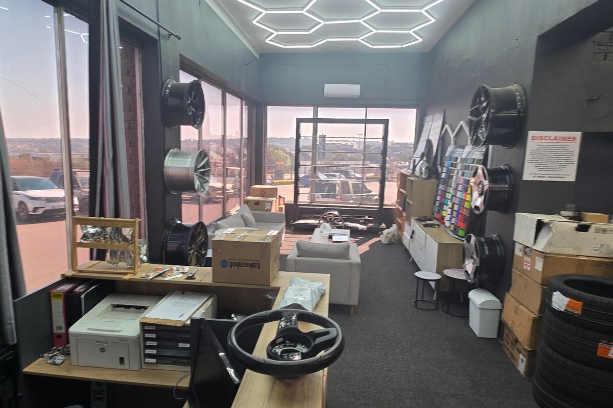 Modern industrial-style office space featuring unique hexagonal LED ceiling lighting, large windows with natural light, and carpeted flooring.