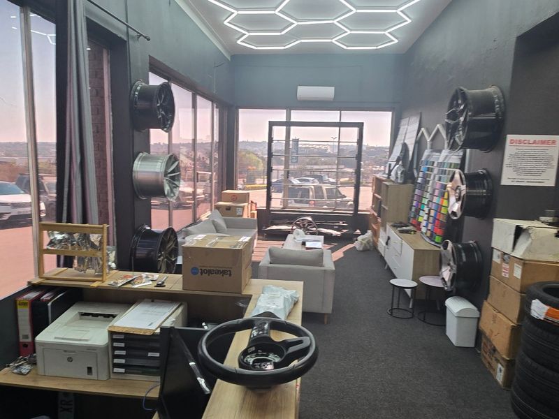 Modern industrial-style office space featuring unique hexagonal LED ceiling lighting, large windows with natural light, and carpeted flooring.