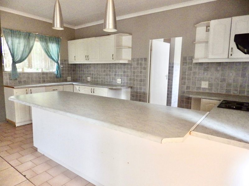 A functional kitchen featuring white cabinetry, laminate countertops, tiled backsplash, and a breakfast bar, offering a clean canvas for potential modern updates.