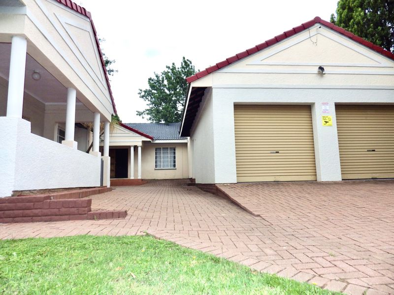 Front view of the property featuring a paved driveway, double garage with roll-up doors, and a covered entrance porch with structural columns.
