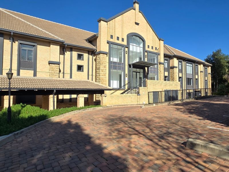 Front elevation of a commercial brick building featuring a paved driveway, covered walkway, and prominent glass entrance.