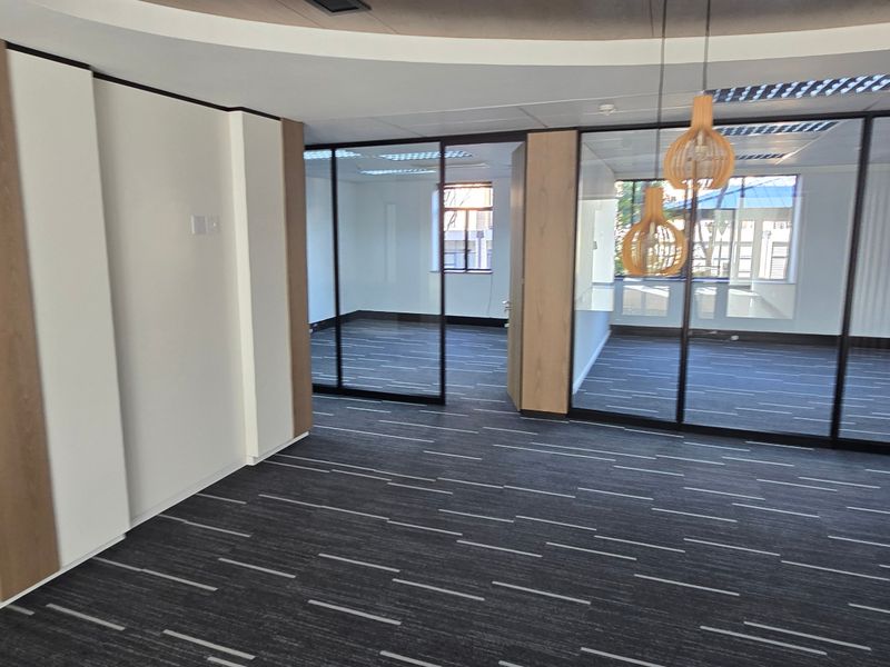 Modern commercial office space featuring glass partitioning, suspended ceilings, and high-quality carpeted flooring, offering a professional and bright work environment.
