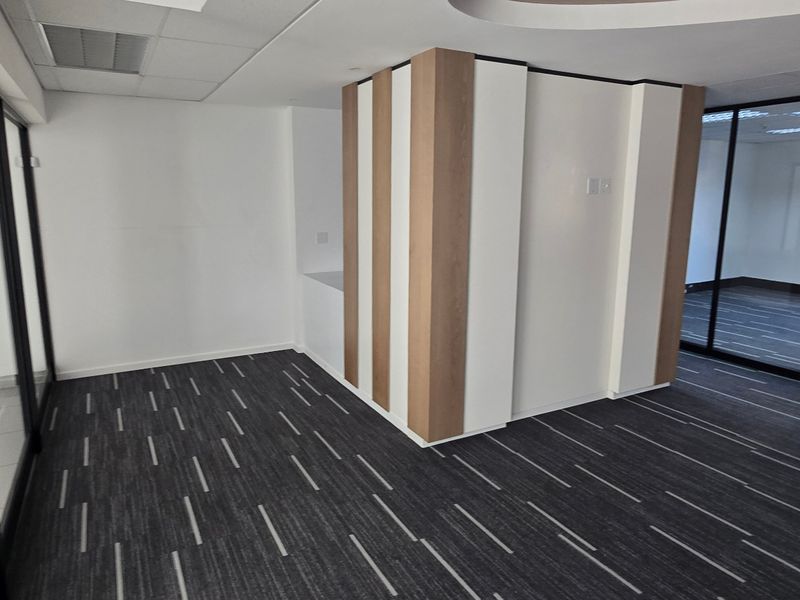 Modern commercial office space featuring glass partitioning, carpet tiles, and a suspended ceiling, offering a clean and professional environment.