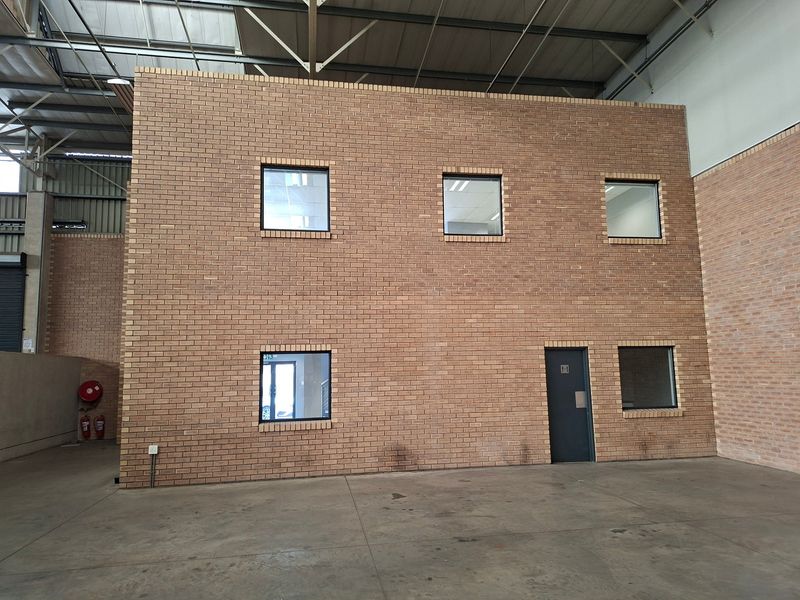 Spacious industrial warehouse interior featuring a double-story face brick office partition, exposed steel roof structure, and durable concrete flooring.