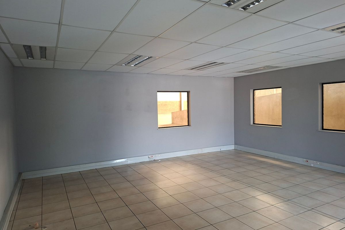 A clean, vacant office space featuring a suspended ceiling, recessed lighting, and neutral tiled flooring, suitable for a variety of industrial or commercial uses.
