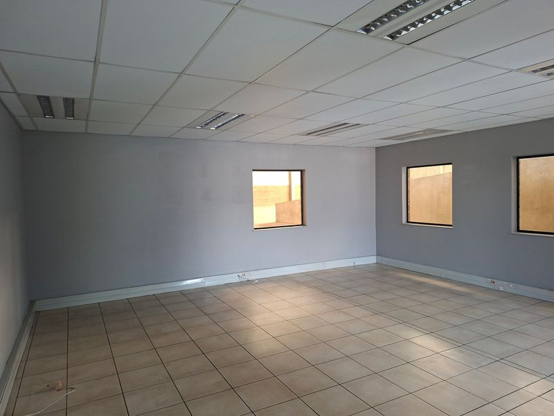 A clean, vacant office space featuring a suspended ceiling, recessed lighting, and neutral tiled flooring, suitable for a variety of industrial or commercial uses.