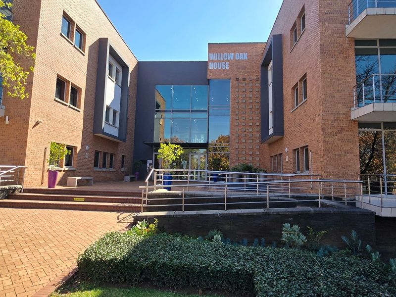 Front elevation of Willow Oak House, featuring a modern brick facade, glass entrance atrium, and accessible ramp with stainless steel railings.