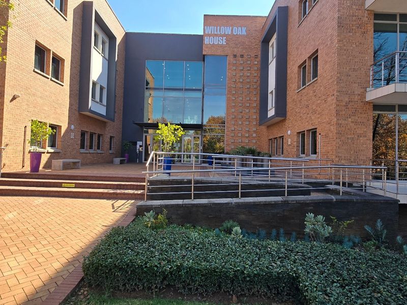 Front entrance view of Willow Oak House, featuring a modern brick facade, glass atrium, and accessible ramp entry.