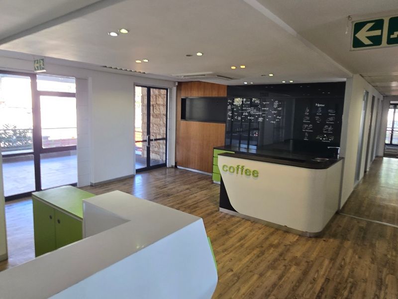 Open-plan commercial space featuring a built-in service counter, laminate flooring, and recessed lighting, suitable for a cafe or reception area.