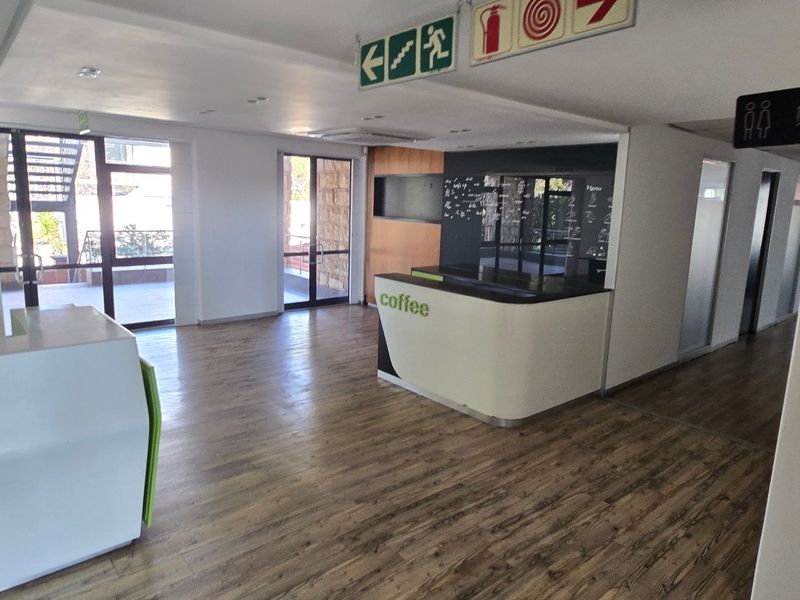 Open-plan commercial reception and coffee service area featuring laminate flooring, built-in service counters, and direct access to outdoor patio space.