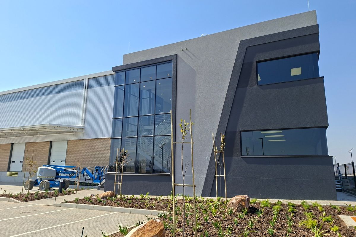 Modern industrial facility featuring a striking double-storey glass facade, metal cladding, integrated loading bays, and professional landscaping.