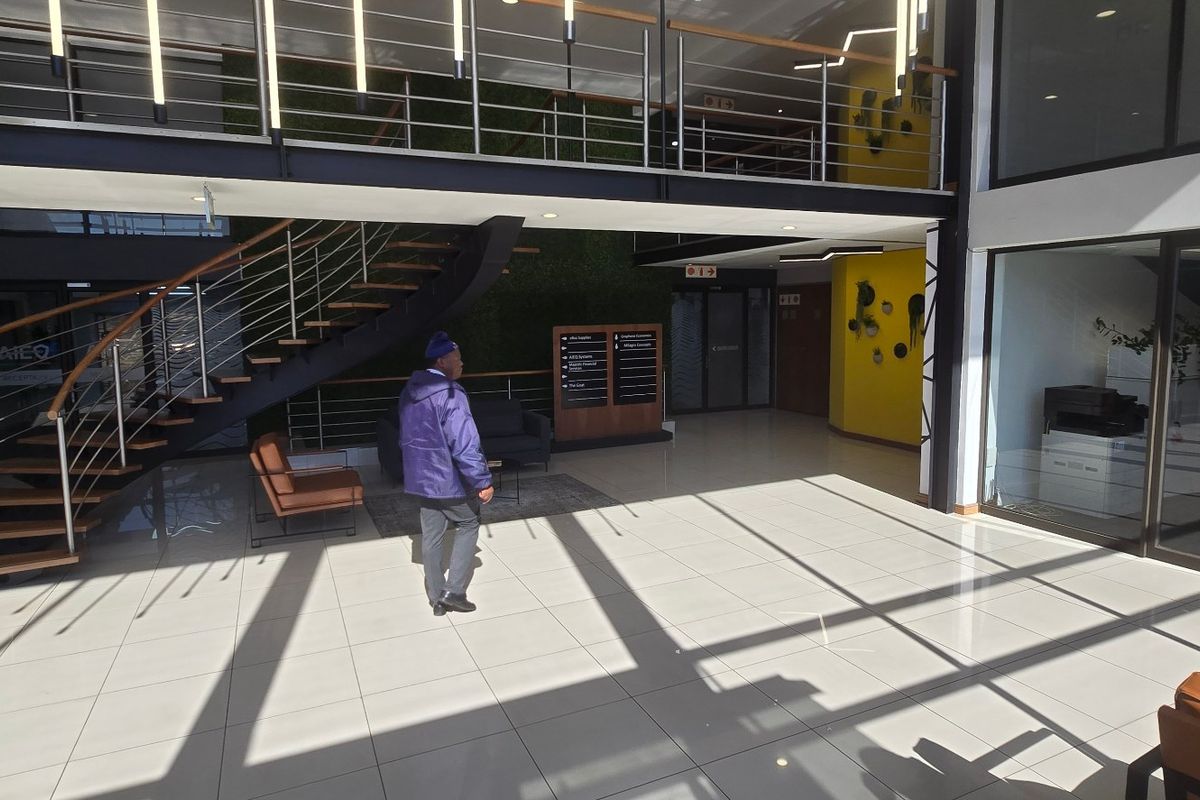 Modern commercial building entrance featuring a grand staircase, tiled flooring, and a mezzanine level with contemporary architectural finishes.