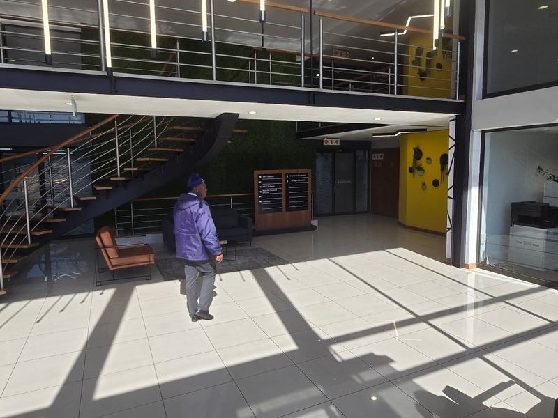 Modern commercial building entrance featuring a grand staircase, tiled flooring, and a mezzanine level with contemporary architectural finishes.