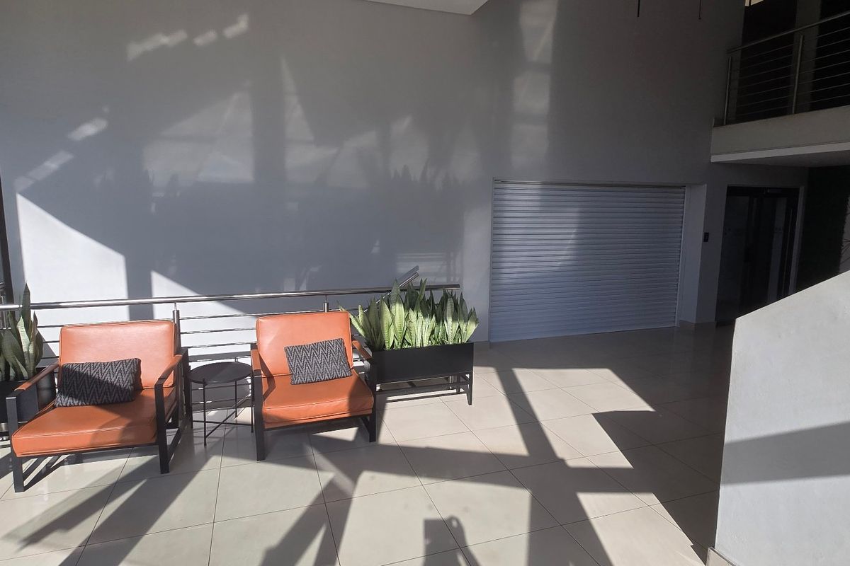 Spacious commercial entrance area featuring tiled flooring, a mezzanine level, and a secure roller shutter door, providing a bright and modern reception space.