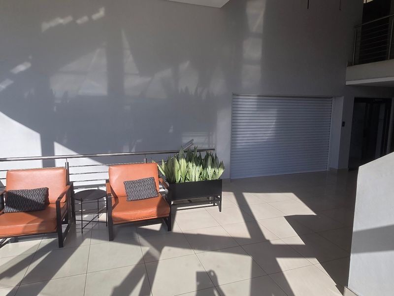 Spacious commercial entrance area featuring tiled flooring, a mezzanine level, and a secure roller shutter door, providing a bright and modern reception space.