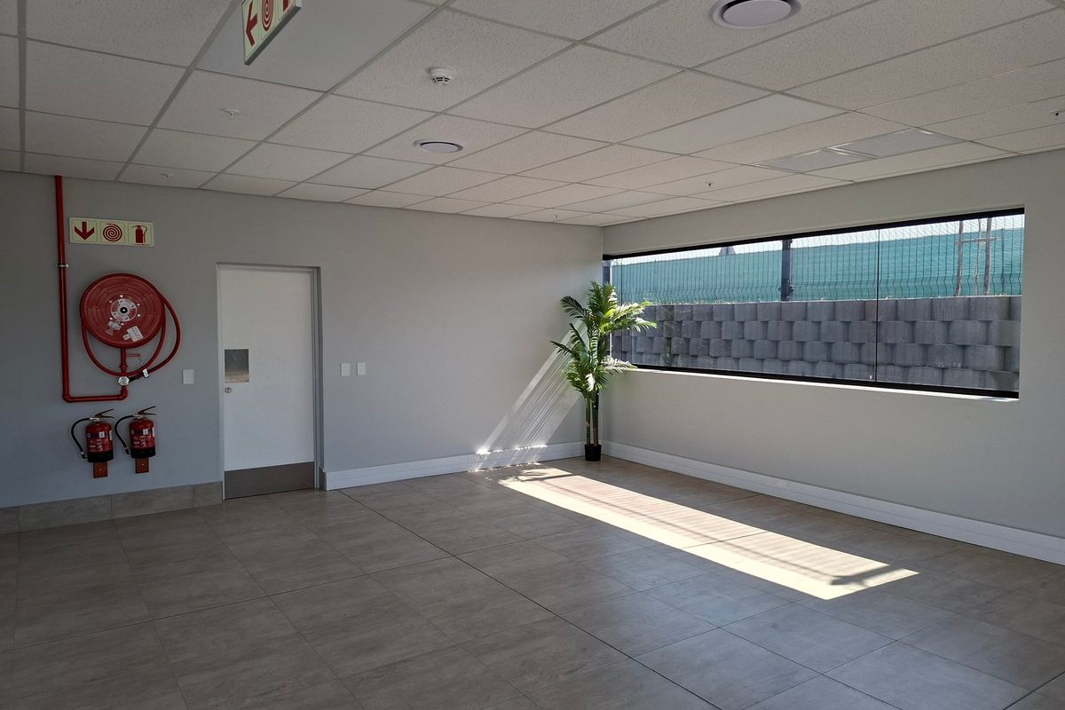 A clean, vacant office space featuring tiled flooring, a suspended ceiling, and integrated fire safety equipment, offering a bright and professional work environment.