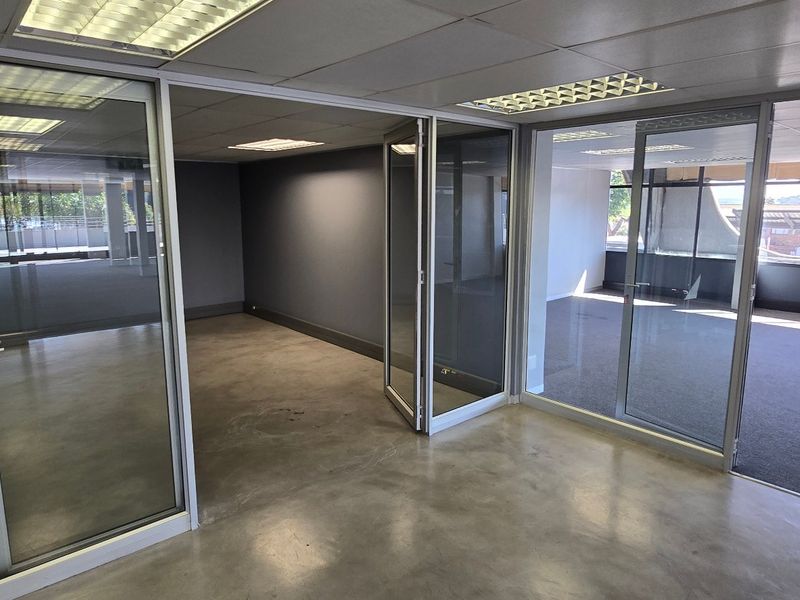 Vacant commercial office space featuring glass partitions, polished concrete and carpet flooring, and recessed ceiling lighting, offering a clean and professional layout.