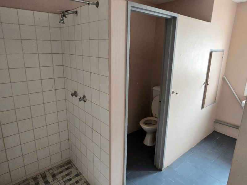 A functional bathroom featuring a tiled shower enclosure and a separate toilet area with basic finishes.