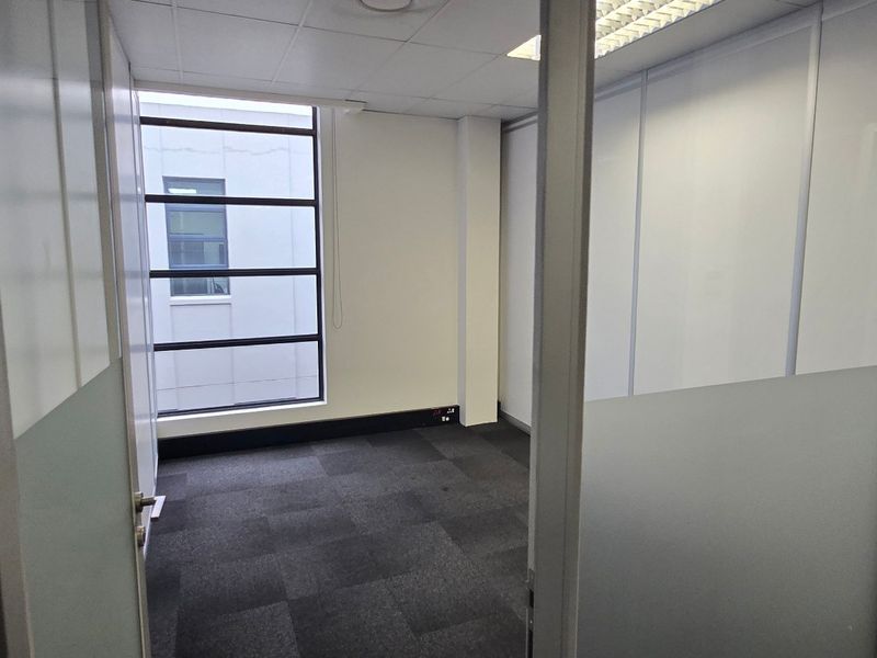 A vacant, modern office space featuring carpet tiles, suspended ceilings, and glass partitioning, offering a clean and professional environment.