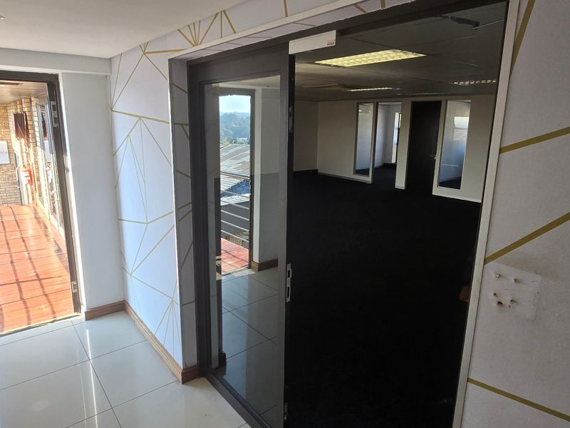 Entrance area featuring tiled flooring, patterned wallpaper, and a glass sliding door leading into an open-plan office space.