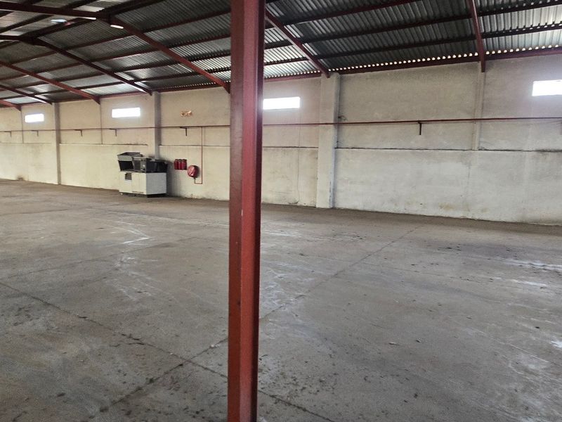 Spacious industrial warehouse unit featuring high ceilings, concrete flooring, steel support columns, and natural light from high-level windows.