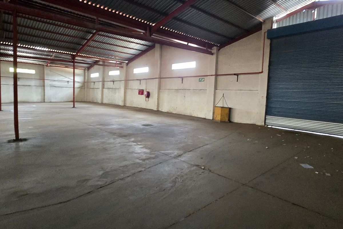 Spacious industrial warehouse featuring high ceilings, concrete flooring, and a large roller shutter door for easy access.