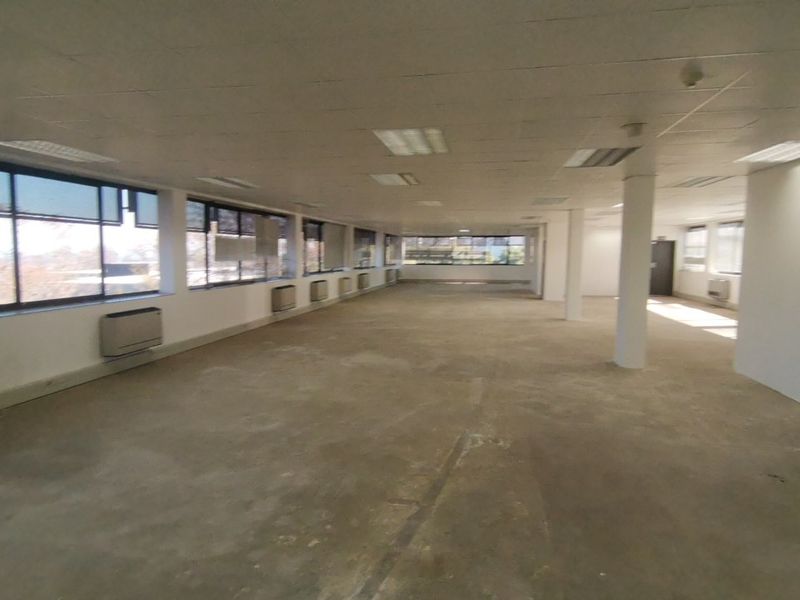A spacious, vacant open-plan office area featuring large windows, suspended ceilings with recessed lighting, and integrated HVAC units, ready for custom fit-out.