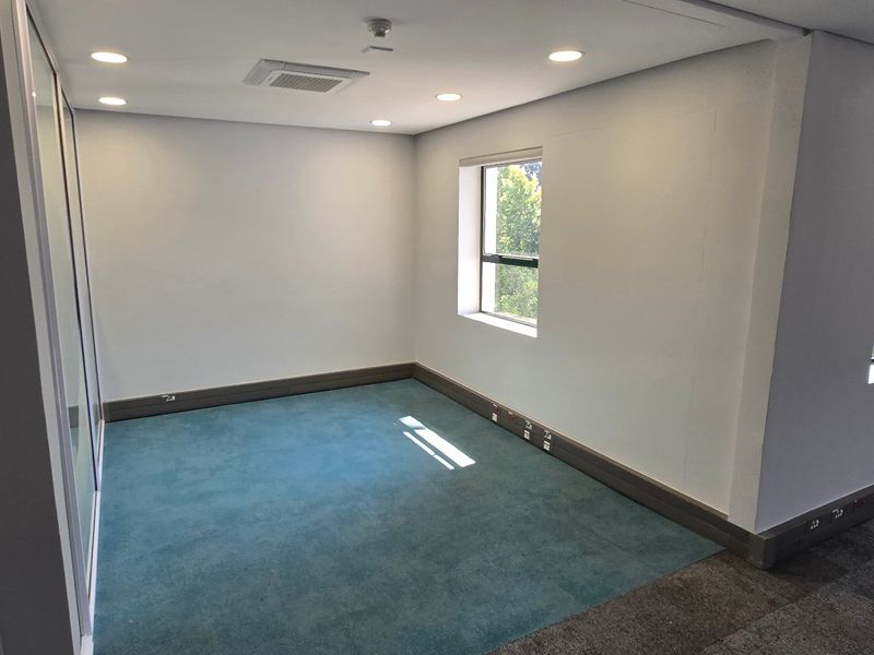 A bright, vacant office space featuring modern recessed lighting, ducted air conditioning, and carpeted flooring with integrated power skirting.