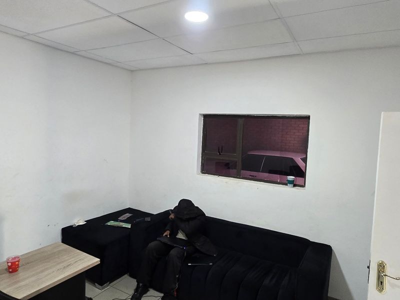 A functional office space featuring a suspended ceiling, recessed lighting, and an aluminium-framed window, suitable for a professional work environment.