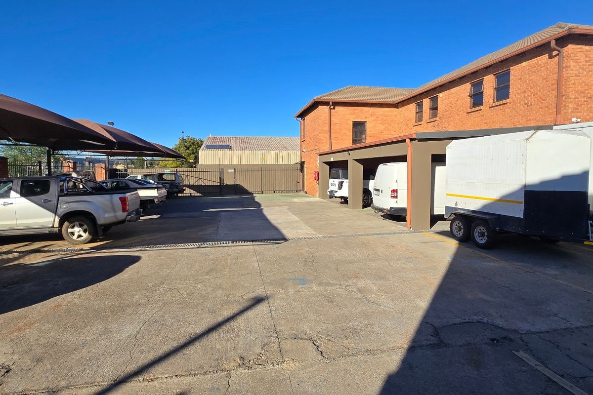 Industrial property exterior featuring a paved parking area with shade cloth carports and secure perimeter fencing.