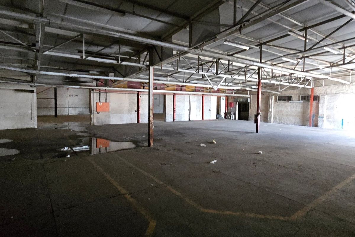Large industrial warehouse space featuring exposed steel roof trusses, concrete flooring, and open-plan layout suitable for storage or manufacturing operations.