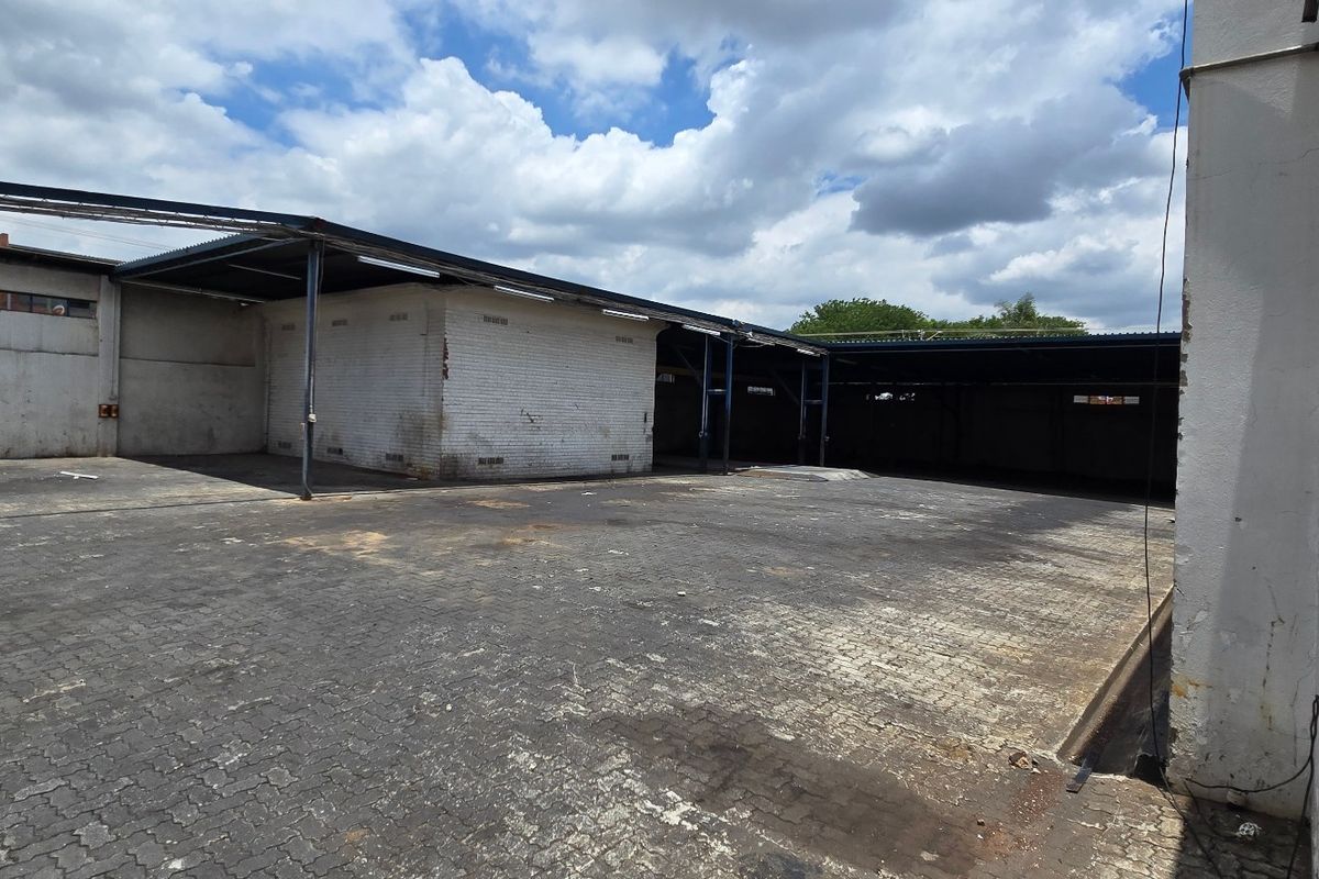 Spacious industrial yard featuring paved ground, covered loading bays, and robust steel-supported structures, suitable for logistics or storage operations.