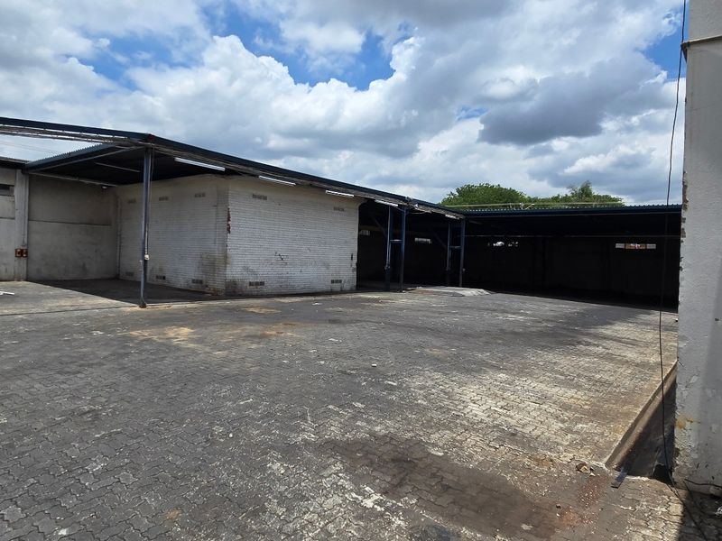 Spacious industrial yard featuring paved ground, covered loading bays, and robust steel-supported structures, suitable for logistics or storage operations.