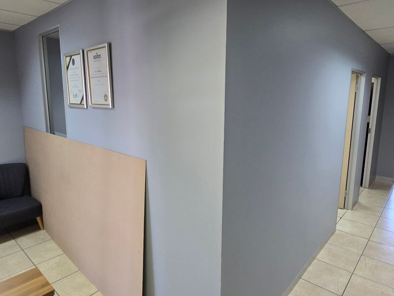 A functional commercial office space featuring ceramic tiled flooring, suspended ceiling panels, and neutral wall finishes, suitable for professional use.