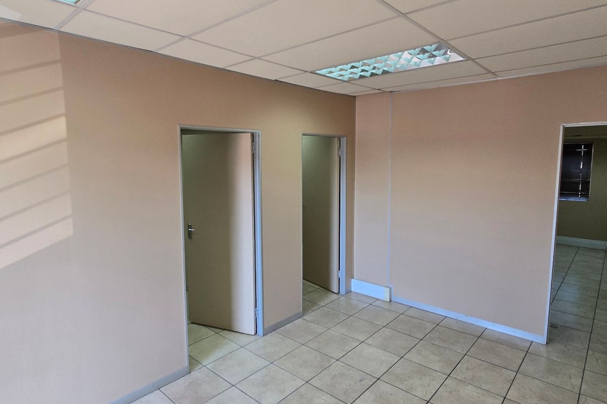 An empty commercial office space featuring neutral walls, ceramic tiled flooring, and a suspended ceiling with recessed lighting.