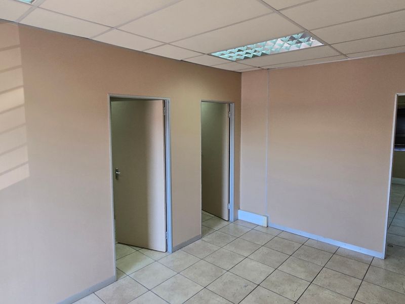 An empty commercial office space featuring neutral walls, ceramic tiled flooring, and a suspended ceiling with recessed lighting.