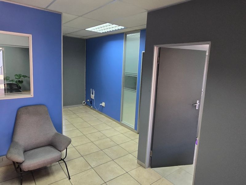 A functional office space featuring ceramic floor tiles, a suspended ceiling with recessed lighting, and internal glass partitioning for a professional layout.