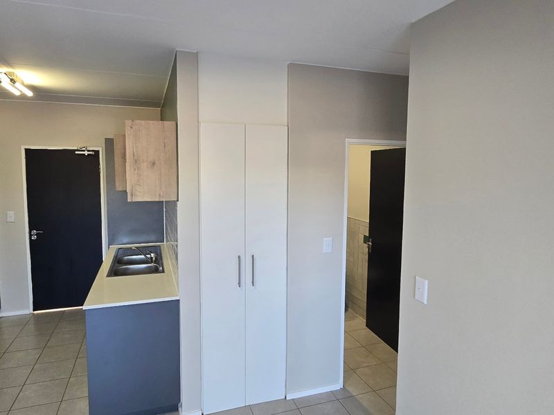 Modern kitchen featuring dark grey cabinetry, light wood-look upper cabinets, electric hob, built-in oven, and a double bowl sink with tiled flooring.