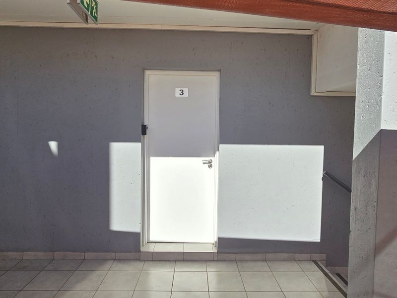 A clean apartment entrance area featuring tiled flooring and a secure unit door.