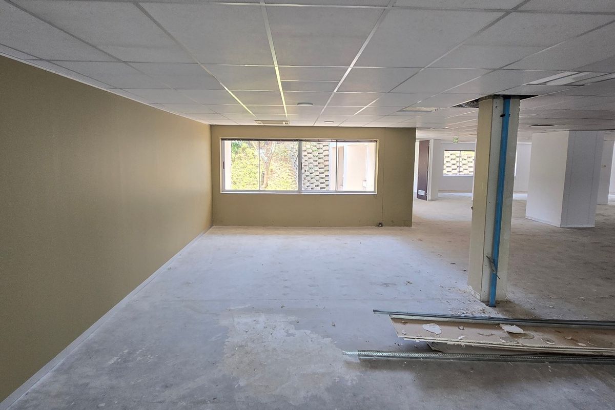 Expansive open-plan commercial office space featuring a suspended ceiling, structural columns, and large windows, currently in a shell condition ready for fit-out.