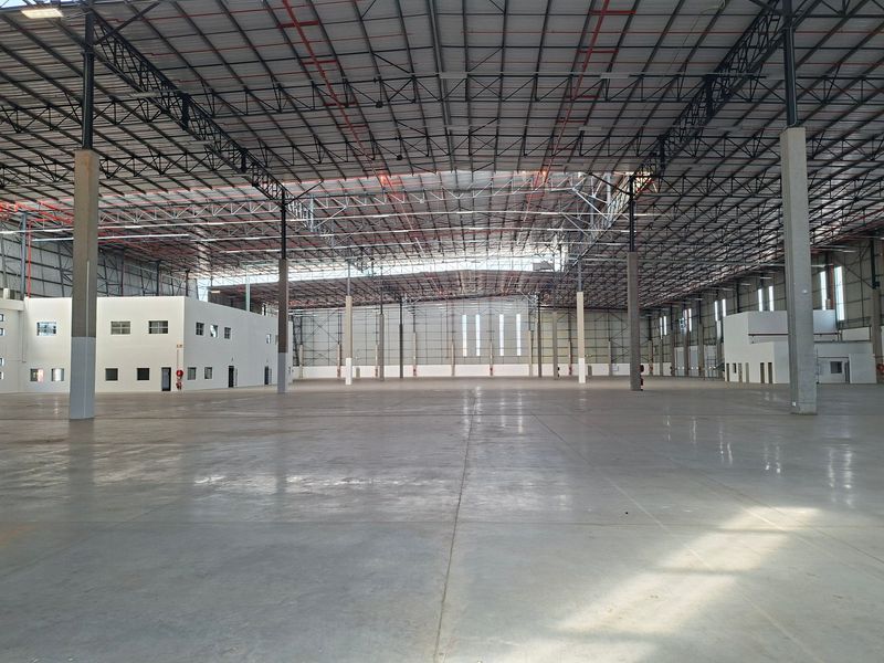 Expansive industrial warehouse space featuring high-clearance steel truss roofing, polished concrete flooring, and an integrated internal office structure.
