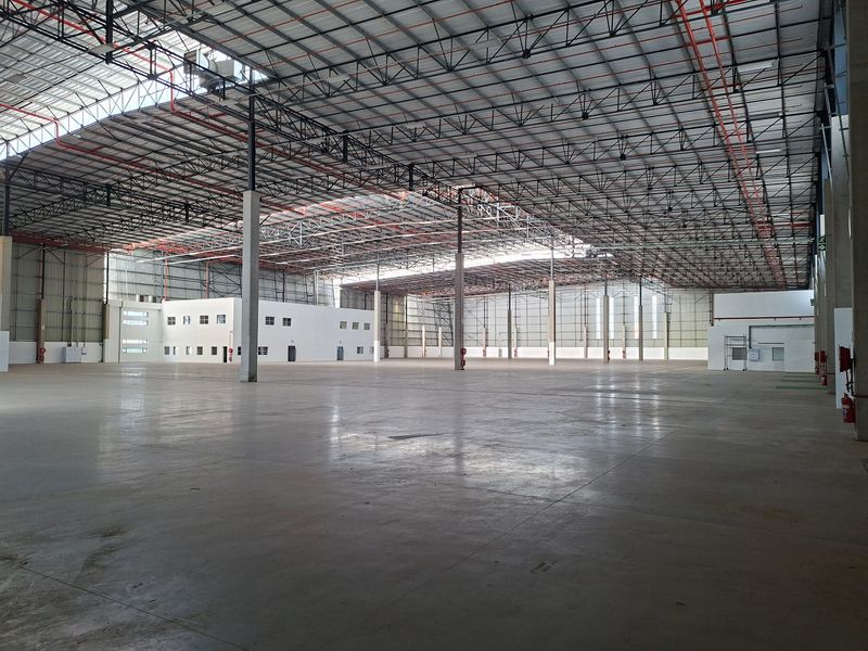 Expansive industrial warehouse space featuring high ceilings with exposed steel trusses, polished concrete flooring, integrated fire sprinkler system, and a dedicated internal office structure.