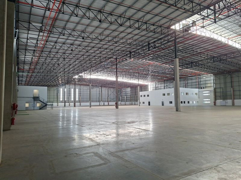 Expansive industrial warehouse space featuring high ceilings with exposed steel trusses, polished concrete flooring, and an integrated internal office structure.