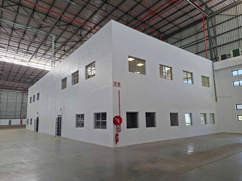 Spacious industrial warehouse interior featuring a clean, modern two-story office block, concrete flooring, and exposed steel roof structure with integrated fire safety systems.
