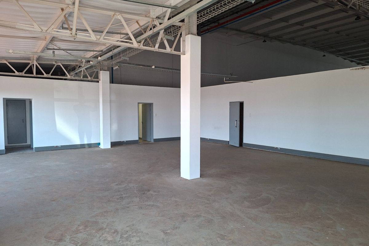 Spacious industrial utility area featuring exposed steel roof trusses, concrete columns, and durable concrete flooring, suitable for various commercial or storage applications.