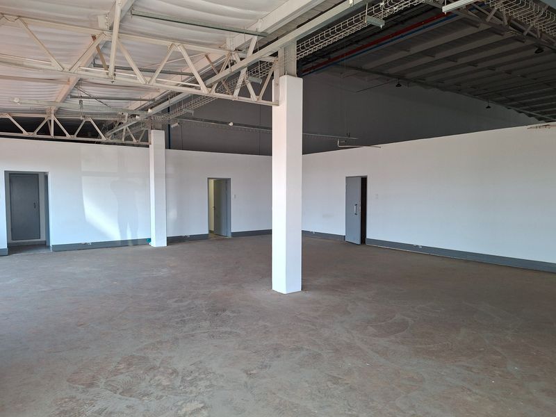 Spacious industrial utility area featuring exposed steel roof trusses, concrete columns, and durable concrete flooring, suitable for various commercial or storage applications.